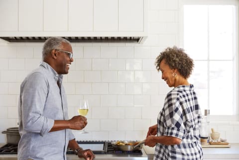 Older couple laughing, talking, and cooking in kitchen