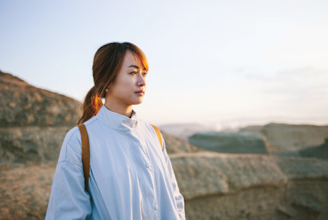 Woman looking thoughtful by herself outdoors in mountain range during fall / winter Woman looking thoughtful by herself outdoors in mountain range during fall / winter
