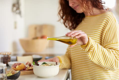 woman pouring sunflower oil into a salad