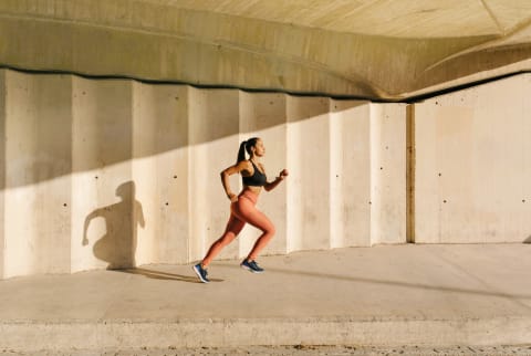 Athletic Woman Running On Street In Sunlight