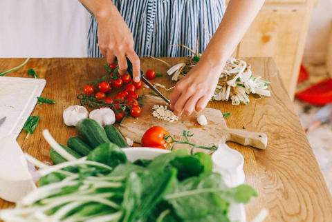 Woman Chopping up Garlic, Tomatoes, and Other Veggies