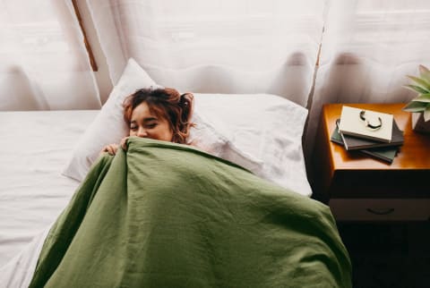 Woman in bed with comforter next to window