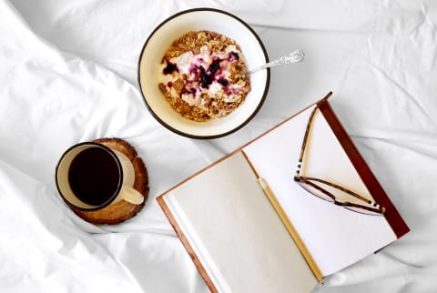 overhead view of a healthy breakfast in bed while journaling