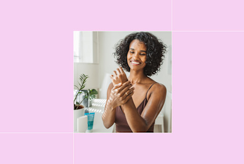 image of woman putting lotion on her hands on pink background
