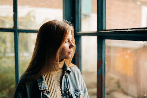 woman looking out window sad