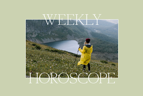 Woman in yellow rain jacket with a hiking stick stands on a hillside overlooking a vista with a lake Woman in yellow rain jacket with a hiking stick stands on a hillside overlooking a vista with a lake