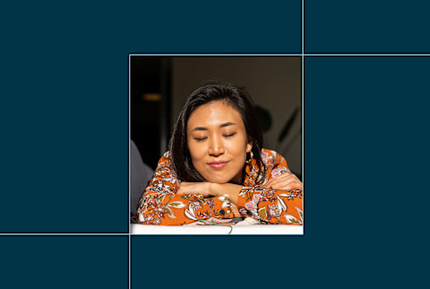 photo of woman with arms crossed leaning on table on blue background