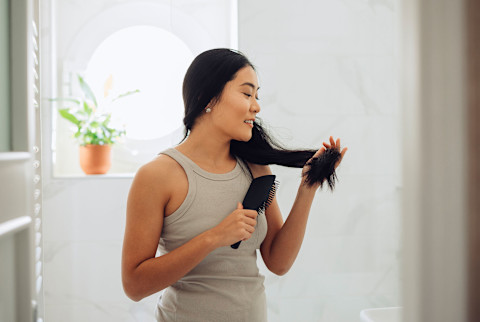Woman brushing her hair - evaluating hair loss