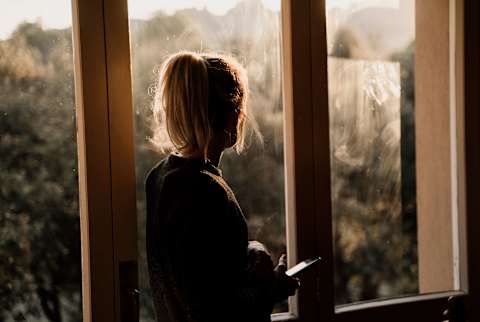 A woman looking out the window mournfully.
