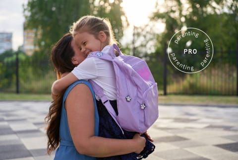 Young girl with backpack embracing her mother