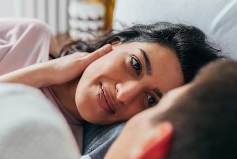 Couple laying in bed looking at each other