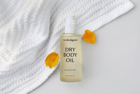 mindbodygreen dry body oil fragrance free on white towel with flower