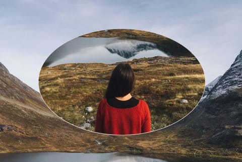 Woman stands against a glacial lake and mountains in Norway