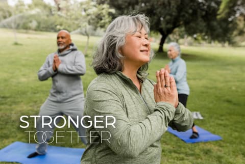 Older woman does yoga in a park with friends