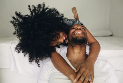 Couple looking at each other lovingly sitting on end of bed