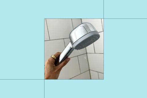 photo of writer's hand holding a handheld showerhead on a teal blue background