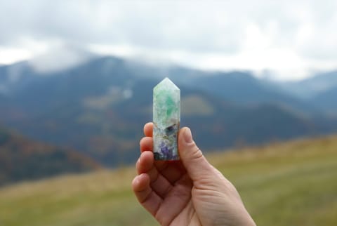 woman holding crystal over a mountain