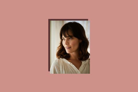 photo of dark haired woman smiling on pink background