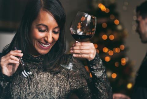 women at holiday party holding wine glass