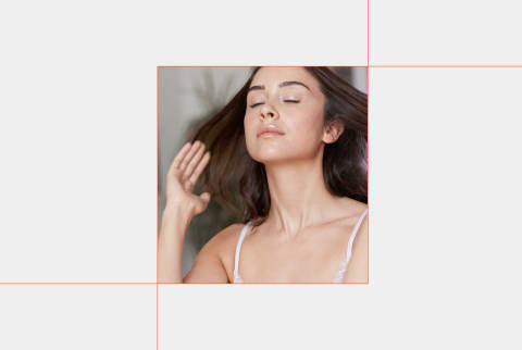 photo of woman with brown hair with eyes closed on light grey background