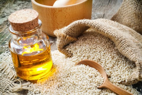 Sesame seeds in sack and bottle of oil on table