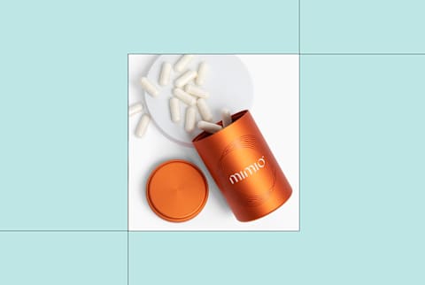 Mimio supplement tin open with capsules spilling out onto background