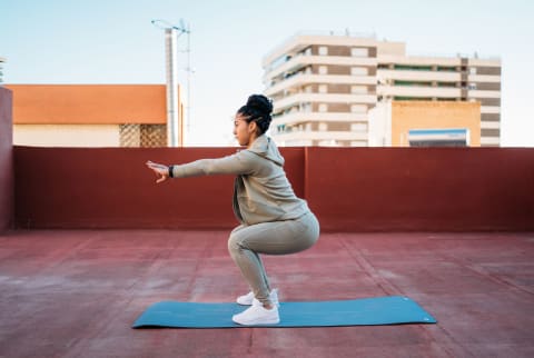 Active Woman Doing Squats On Mat During Workout