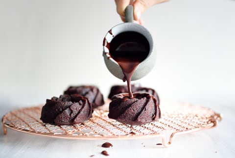pouring chocolate over mini chocolate cakes