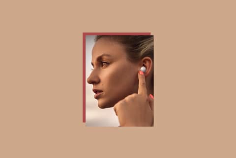 samsung galaxy buds2 review image of women with headphones in ears pressing button