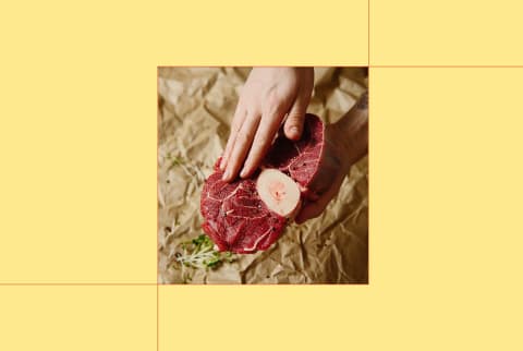 image of hand preparing raw steak on yellow background