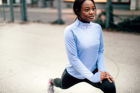 Black woman stretching / working out outside during fall / winter