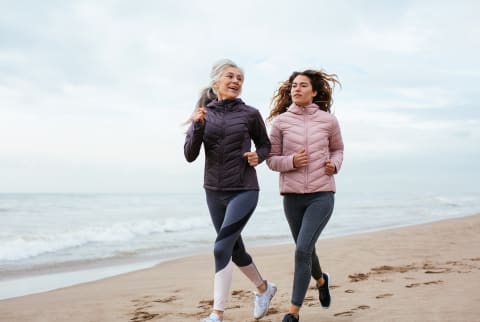 Older woman and her daughter running on the beach