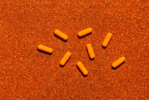 Pills and supplements on a glittery orange background
