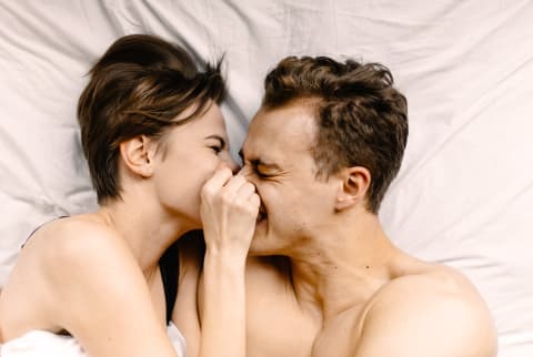 Young white couple in bed laughing