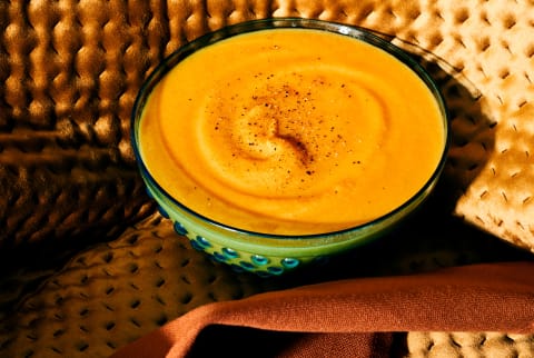 Pumpkin soup on golden velvet and tea towel