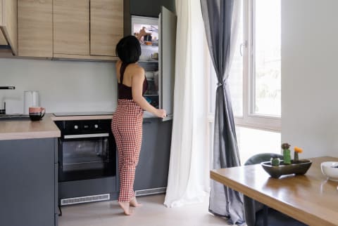 Asian woman in a kitchen looking into fridge