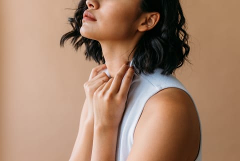 Woman grasping her shirt collar in contemplation