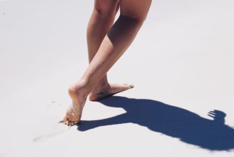 Woman walking barefoot on the beach