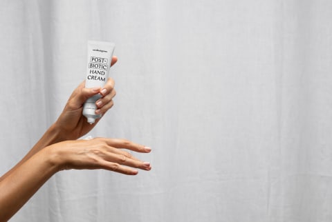 Woman applies mbg Post-Biotic Hand Cream to hands