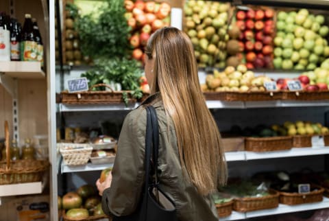 Woman with long hair shops in the produce section of a grocery store