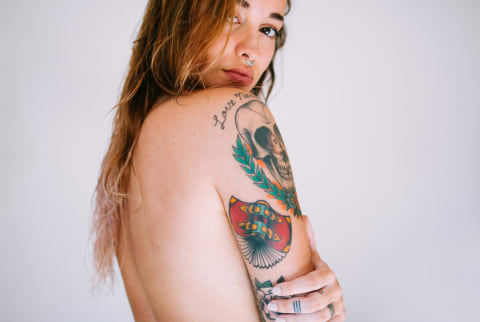 Woman with arm tattoos looking at camera Woman with arm tattoos looking at camera