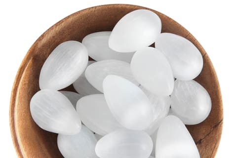 white selenite stones in wooden bowl