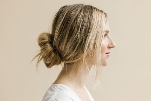 Young Stylish Woman Standing In Front Of Partial Painted Background In Studio