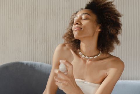 Woman misting herself with fragrance