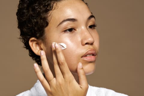 Young Woman Applying Cream On Face