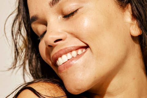 Close up of smiling woman with closed eyes and glowing/dewy skin