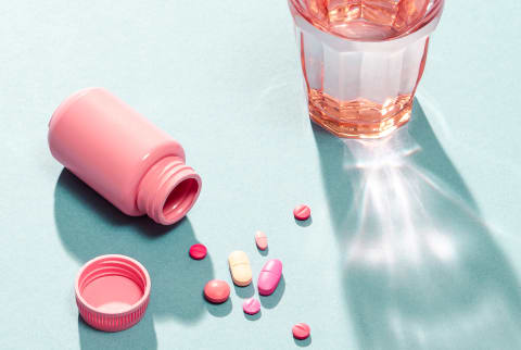 Pills, Capsules, and Vitamins on a Surface with a Glass of Water