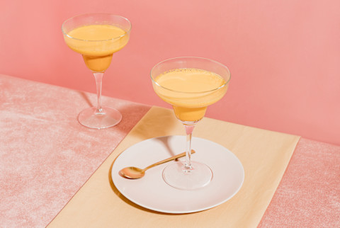Peach Smoothie in a Fancy Glass on a Pink Table Peach Smoothie in a Fancy Glass on a Pink Table