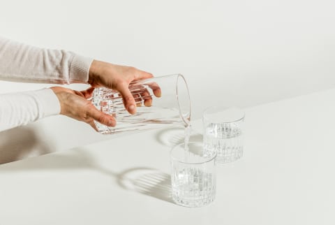 Hand Pouring Water into a Glass Alluding to Intermittent Fasting