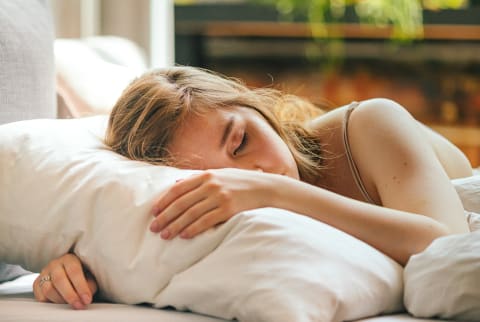 Young Woman Asleep in Bed on Sunny Morning